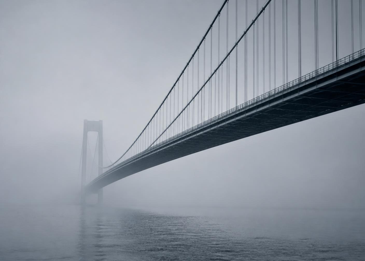 Suspension bridge over water in morning haze